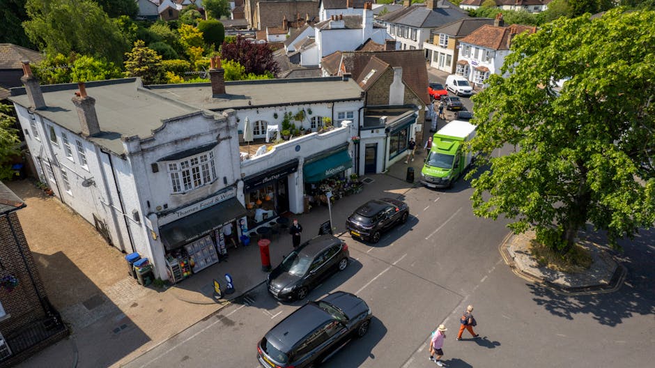 A street scene in Wimbledon Hill Road showing several parked cars along the pavement, with a mix of sedans and hatchbacks in various colours including white, red, and black. The street is lined with l